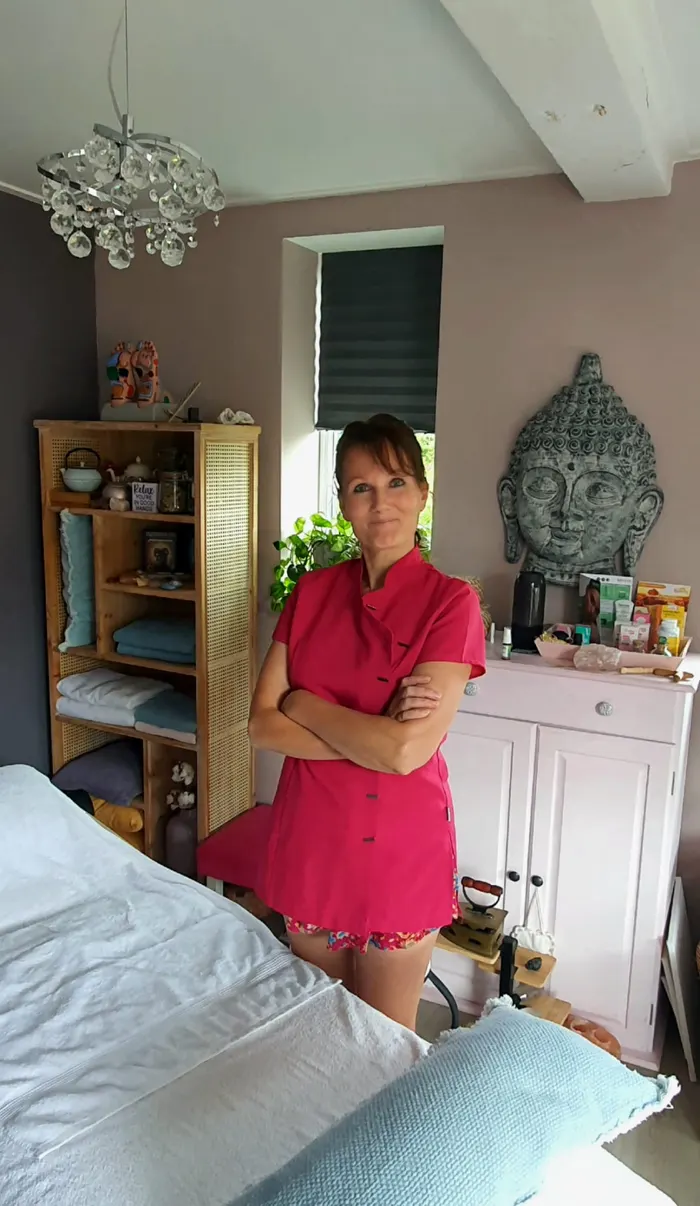 Patricia de Beer in haar behandelruimte, naast de behandeltafel met opgevouwen handdoeken.